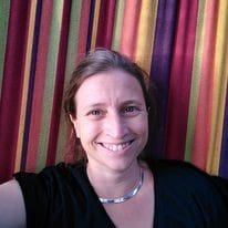 Selfie of a woman, smiling at the camera, with a striped background behind her