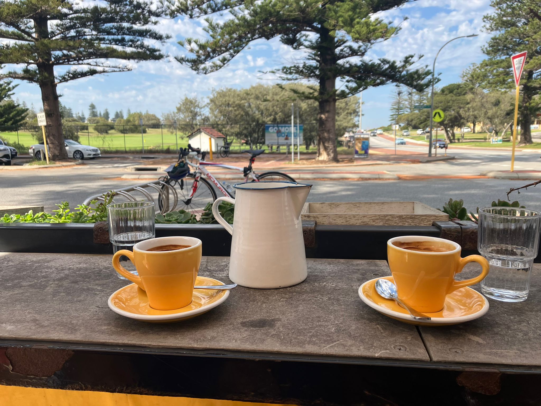 Two yellow cups of coffee on a table by an Australian intersection.