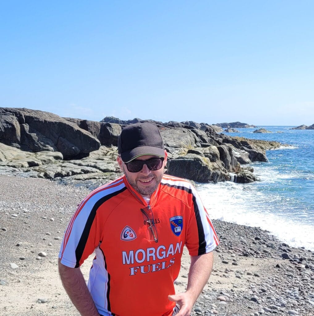 A man in a football shirt on a beach on Iona
