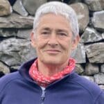 Person with greying hair and a pink neck scarf and blue fleece