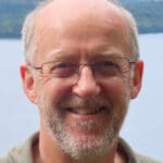 Man smiling at camera with a body of water in the background
