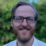 Man with glasses and beard smiling at camera