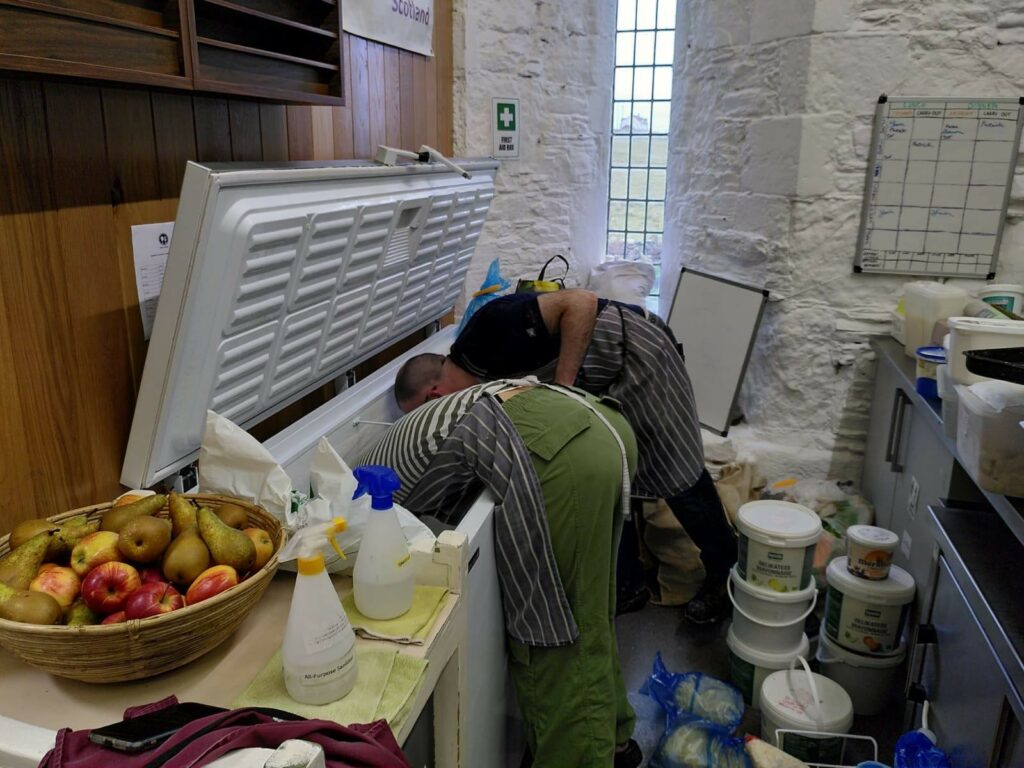 Two people searching in a freezer for a pea