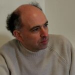 Man looking into middle distance, wearing a cream jumper.