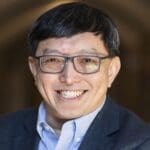 Swee Hong - man with blue shirt and navy blazer smiling at camera, he's also wearing glasses