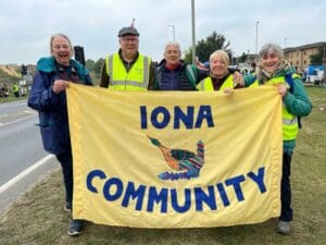 Five people hold an Iona Community banner
