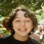 Curly hair smiling woman with a tree in background