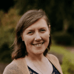 Woman with brown hair, tan cardigan and a navy top