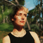 Woman with short blond hair and a black vest looking off camera to the right