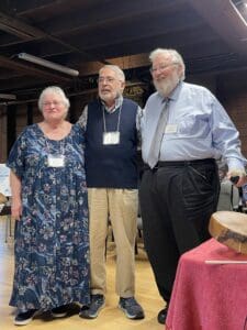 Three people standing together with arms round each other.
