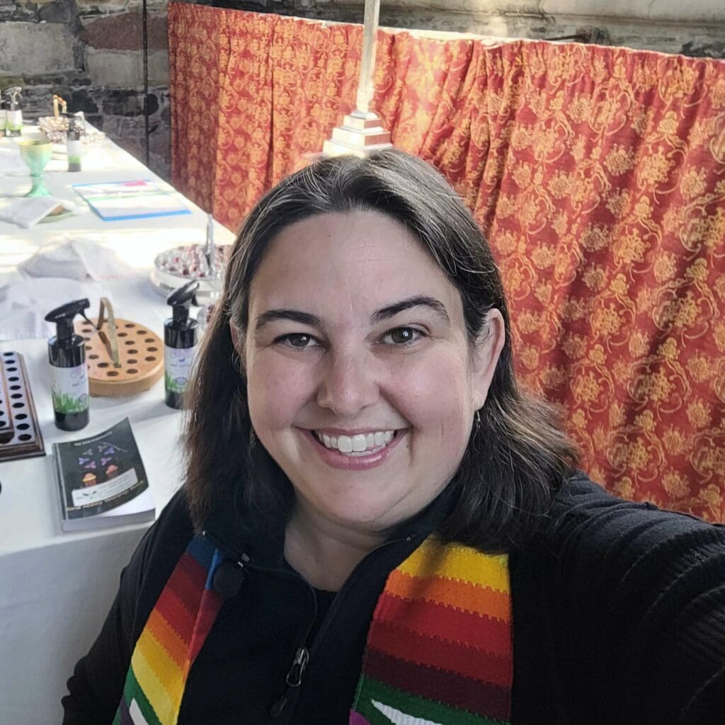 Person wearing a stole smiling at camera standing beside the communion table in Iona Abbey.