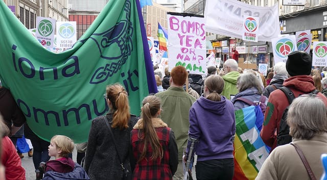 People protesting for peace walking down a street carrying banners