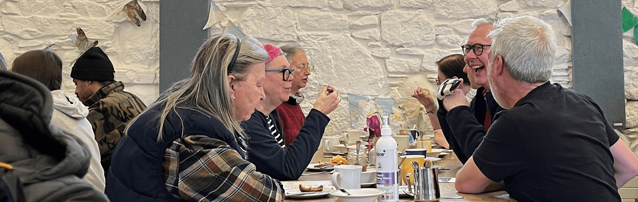 People sitting eating a meal in the refectory of Iona Abbey
